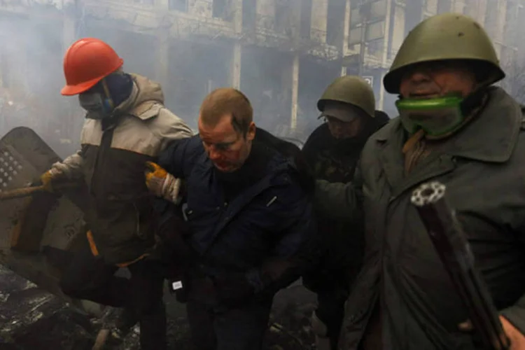Manifestantes contrários ao governo prendem um policial durante confrontos na Praça da Independência em Kiev (Yannis Behrakis/Reuters)