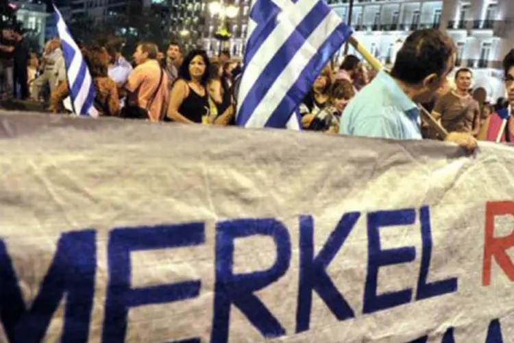 
	Manifestantes exibem cartazes de &quot;Fora, Merkel&quot; em protestos contra a visita da chanceler alem&atilde; a Atenas: pelo menos 30 mil pessoas se reuniram para protestar
 (Louisa Gouliamaki/AFP)