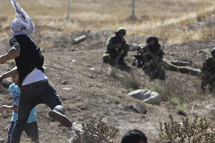 Palestinos atiram pedras contra soldados israelenses durante protesto na Cisjordânia (Abed Omar Qusini/Reuters)