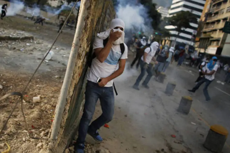 Manifestante tenta se proteger de gás de pimenta durante protesto contra o governo de Nicolás Maduro na praça Altamira, em Caracas, Venezuela (Tomas Bravo/Reuters)