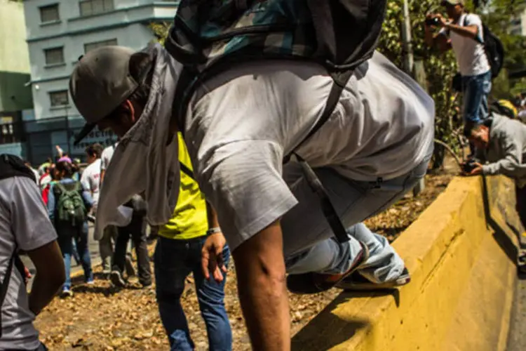 Manifestante pula uma barricada durante um protesto contra o governo de Maduro em Caracas, na Venezuela (Meridith Kohut/Bloomberg)