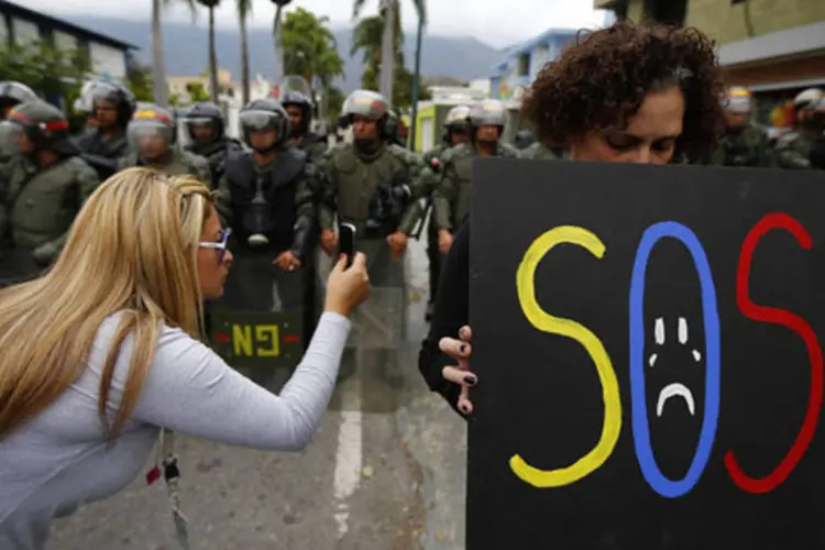 Manifestante segura cartaz durante manifestação perto da embaixada cubana em Caracas, na Venezuela (Jorge Silva/Reuters)
