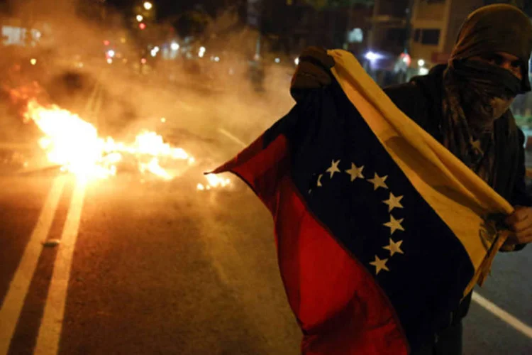Manifestante com a bandeira da Venezuela durante um protesto contra o governo de Nicolás Maduro, em Caracas (Carlos Garcia Rawlins/Reuters)