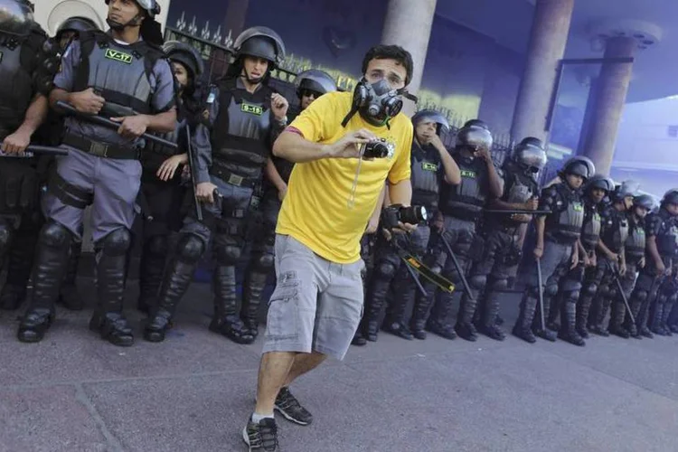 Manifestante filma o confronto com policiais durante protesto na final da Copa do Mundo (Nacho Doce/Reuters)
