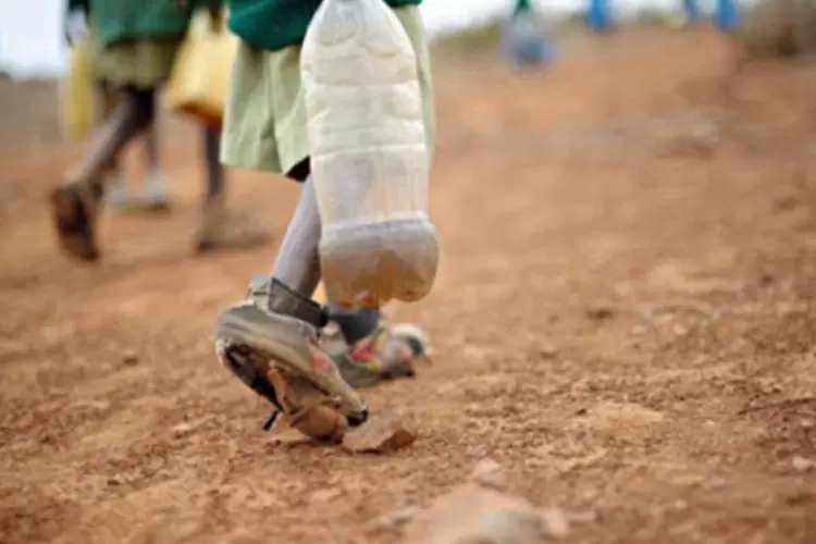 Garoto leva água de rio em garrafa na cidade de Nanyuki, no Quênia: OCDE afirma que ajuda de países ricos é insuficiente na luta contra a pobreza (.)
