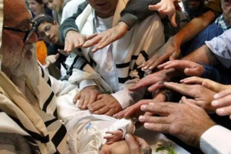 Bebê é abençoado por um grupo de judeus em cerimônia de circuncisão: a Torá, livro sagrado do judaísmo, impõe a circuncisão até 8 dias após o nascimento
 (Menahem Kahana/AFP)