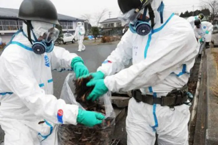 Soldados japoneses coletam folhas em encanamento para análises: as associações de pescadores afirmaram temer o aumento da contaminação do ambiente marinho
 (AFP)