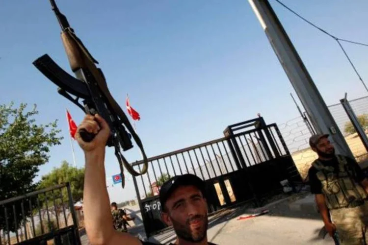 
	Rebelde da organiza&ccedil;&atilde;o Ex&eacute;rcito da S&iacute;ria Livre ergue seu rifle: O helic&oacute;ptero foi a &uacute;ltima aeronave derrubada pelos rebeldes
 (Umit Bektas/Reuters)