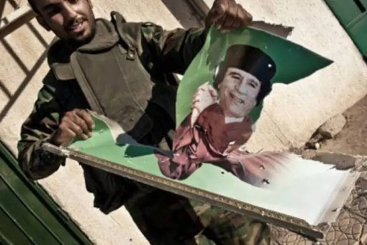 Um rebelde líbio rasga um retrato do líder Muammar Kadafi: Jamis comandava uma das brigadas mais eficazes das tropas leais ao pai  (Colin Summers/AFP)