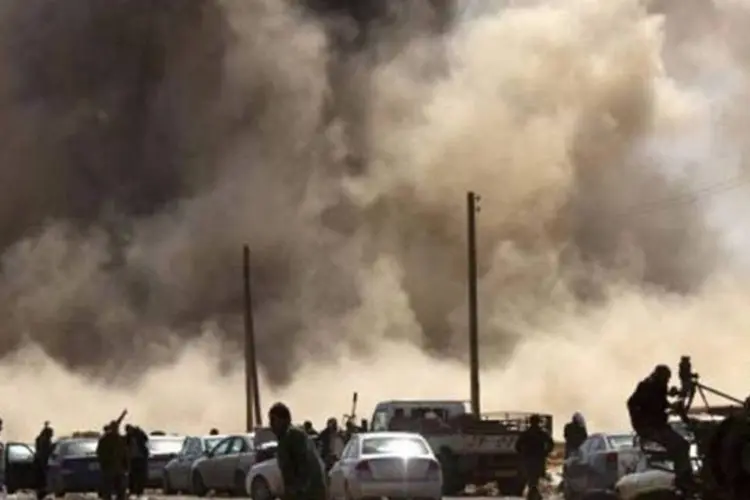 Rebeldes em meio ao ataque da Força Aérea líbia na cidade de Ras Lanuf (Marco Longari/AFP)