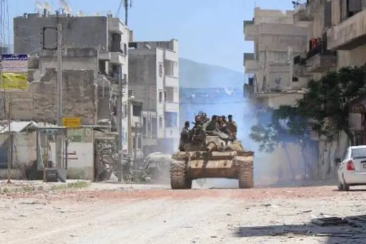 
	Rebeldes se deslocam em um tanque, na S&iacute;ria: pelo menos 28 membros das for&ccedil;as do regime e 24 radicais morreram nos confrontos
 (Ali Nasser/AFP)