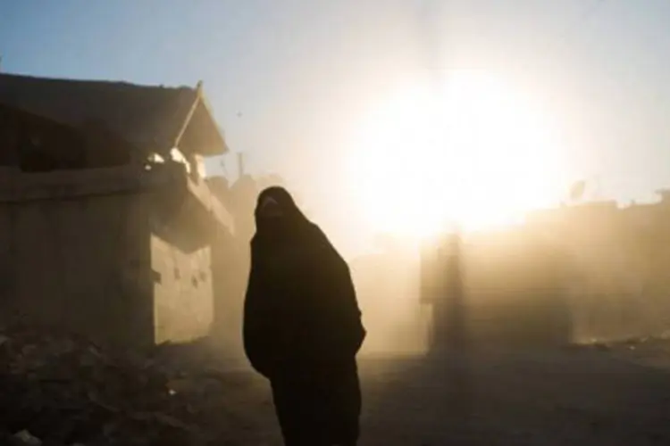 Mulher caminha entre casas destruídas na cidade de Azaz, norte da Síria
 (Phil Moore/AFP)