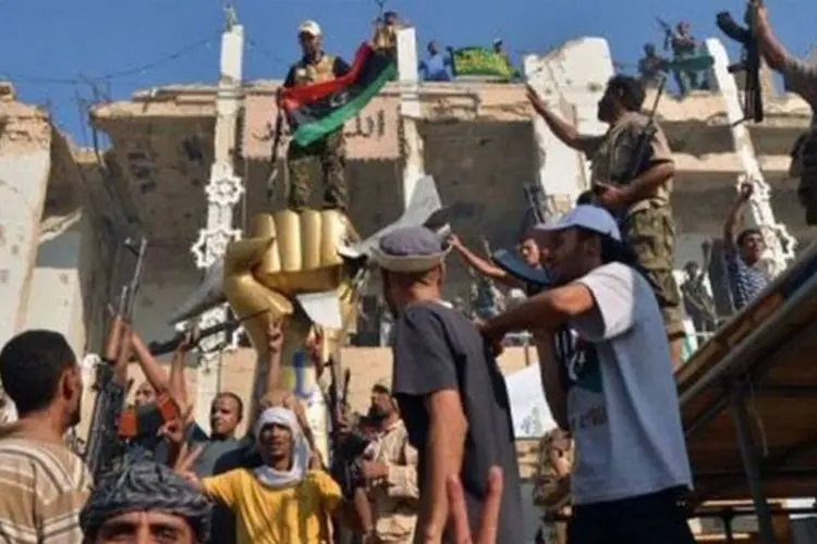 Rebeldes tomam Trípoli e celebram ao redor de estátua de ouro perto do QG de Kadafi, que foi invadido na terça-feira (Filippo Monteforte/AFP)