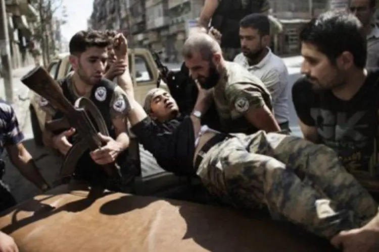 
	Rebeldes ajudam colega ferido em Alepo, na S&iacute;ria: os grupos opositores elevaram o n&uacute;mero total de v&iacute;timas nesta jornada a mais de 80
 (Marco Longari/AFP)