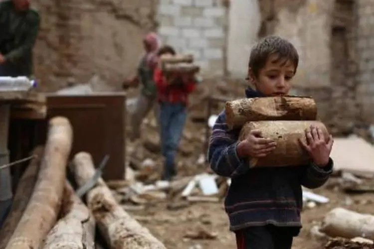 Menino carrega madeira no reduto rebelde sírio de Douma: Israel tem como objetivo impedir as trocas de armas na região (Abd Doumany/AFP)