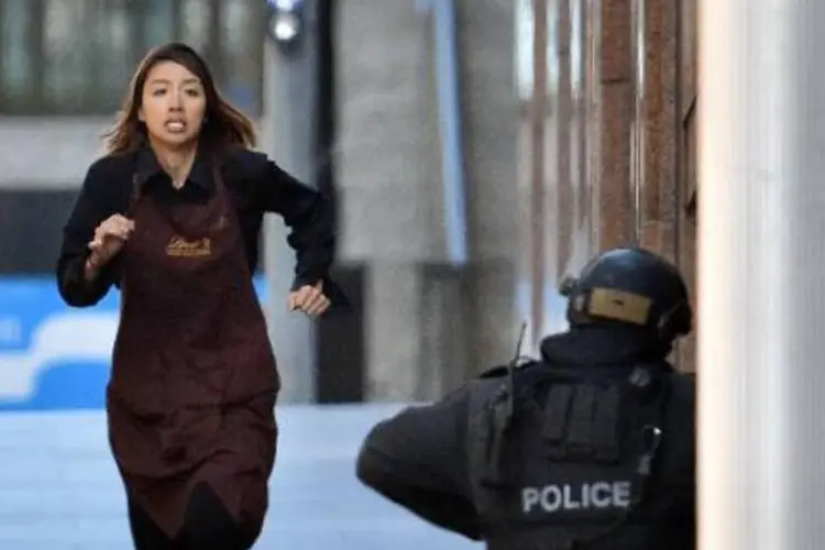 Refém deixa a cafeteria e corre em direção à polícia em Sydney (Saeed Khan/AFP)