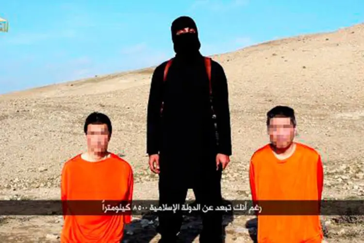 Imagem retirada de um vídeo divulgado pelo EI mostra militante e os dois reféns japoneses Kenji Goto (e) e Haruna Yukawa (d)  (AFP)