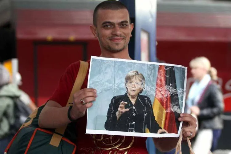 
	Refugiado segura um cartaz de Angela Merkel: Grabar-Kitarovic criticou a forma como o governo croata encara a crise de refugiados, especialmente por ter permitido sua entrada sem controle
 (Gettyimages)