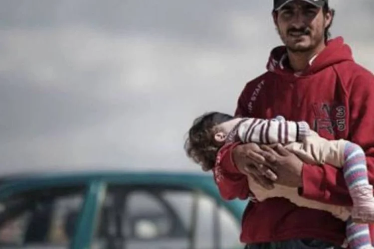 Um argelino com sua filha nos braços aguarda um barco para deixar a Líbia (Gianluigi Guercia/AFP)