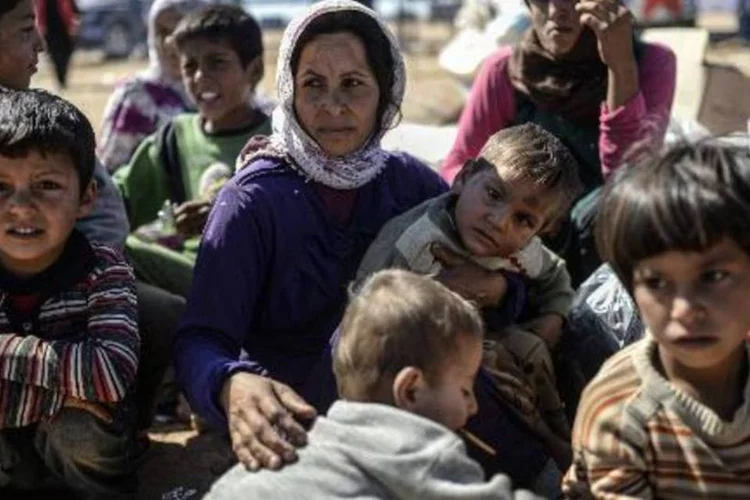 Refugiados sírios curdos descansam após cruzarem a fronteira com a Turquia (Bulent Kilic/AFP)