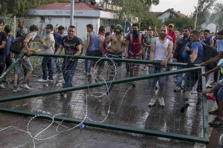 
	Refugiados derrubam uma das barreiras na fronteira da Hungria: quase 500 migrantes estavam no local durante a tarde e 300 participaram nos dist&uacute;rbios
 (Reuters / Marko Djurica)