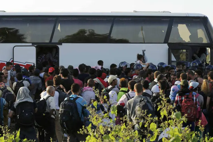 
	Refugiados entrando em &ocirc;nibus na fronteira croata: a chanceler alem&atilde;, Angela Merkel, e seu colega austr&iacute;aco, Werner Faymann, pediram a organiza&ccedil;&atilde;o r&aacute;pida desta c&uacute;pula para entrar em acordo sobre uma divis&atilde;o obrigat&oacute;ria entre os pa&iacute;ses da UE de 120.000 refugiados
 (Reuters / Antonio Bronic)