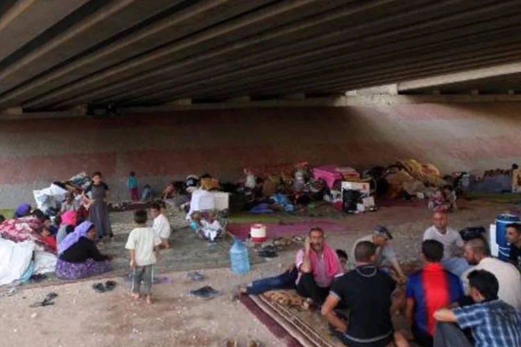 Iraquianos desabrigados da comunidade Yazidi reunidos debaixo de uma ponte que serviu de refúgio, na periferia de Dohuk (Ahmad al-Rubaye/AFP)