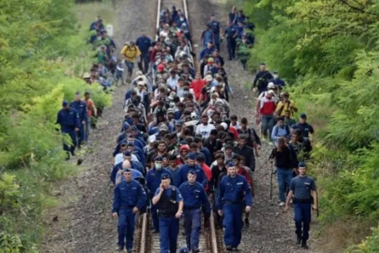 Refugiados de diferentes países são acompanhados por policiais perto da cidade húngara de Szeged, fronteira com a Sérvia (Attila Kisbenede/AFP)