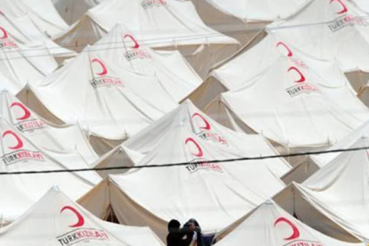 Mulher síria estende roupa no varal no campo de refugiados perto da fronteira da Turquia com a Síria
 (Mustafa Ozer/AFP)