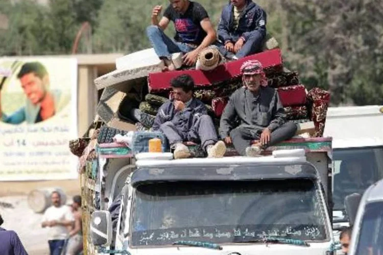 Refugiados sírios na traseira de uma picape passando pelo vale libanês de Bekaa, após deixar a cidade de Arsal rumo à Síria (Joseph Eid/AFP)