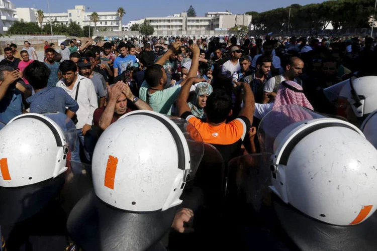 
	Refugiados s&iacute;rios entram em confronto com policiais na Gr&eacute;cia: durante espera em um est&aacute;dio de futebol para obter documentos, algumas pessoas desmaiaram pela aglomera&ccedil;&atilde;o e altas temperaturas. Outras gritaram em protesto contra a falta de comida e m&aacute;s condi&ccedil;&otilde;es
 (Yannis Behrakis)