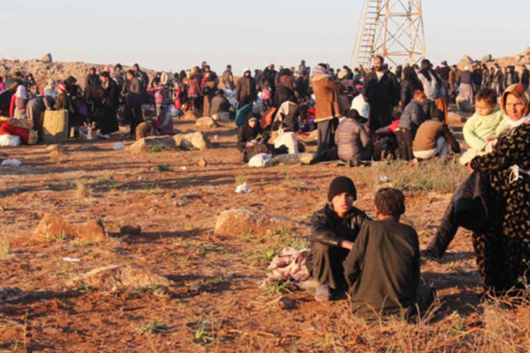 Sírios fugindo da violência aguardam para entrar na Turquia, na fronteira próxima do vila de Shamm Alqrain, próxima de Alepo (Mahmoud Hebbo/Reuters)