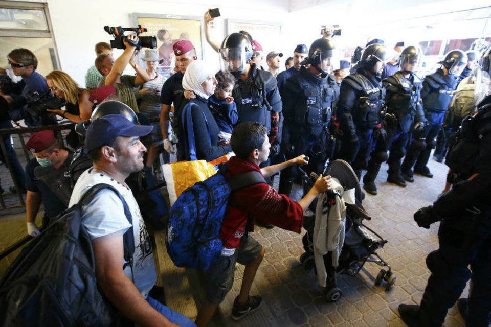 Refugiados começam a descer de trem parado em cidade húngara
