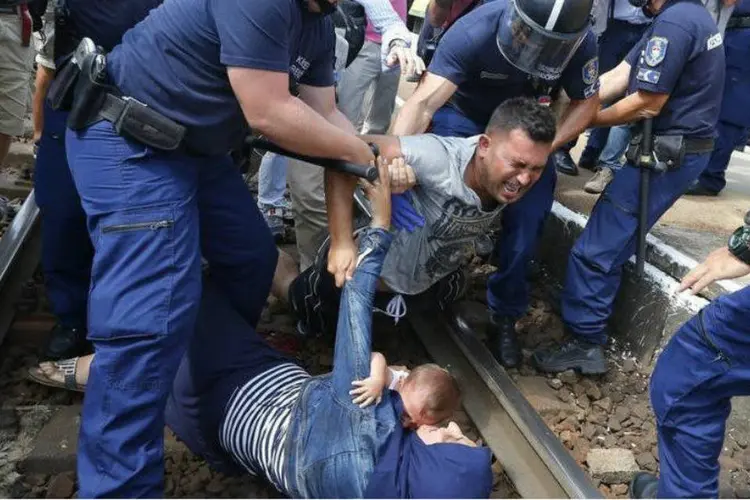 
	Policiais h&uacute;ngaros det&ecirc;m refugiados nos trilhos de trem na cidade de Bicske
 (REUTERS/Laszlo Balogh)