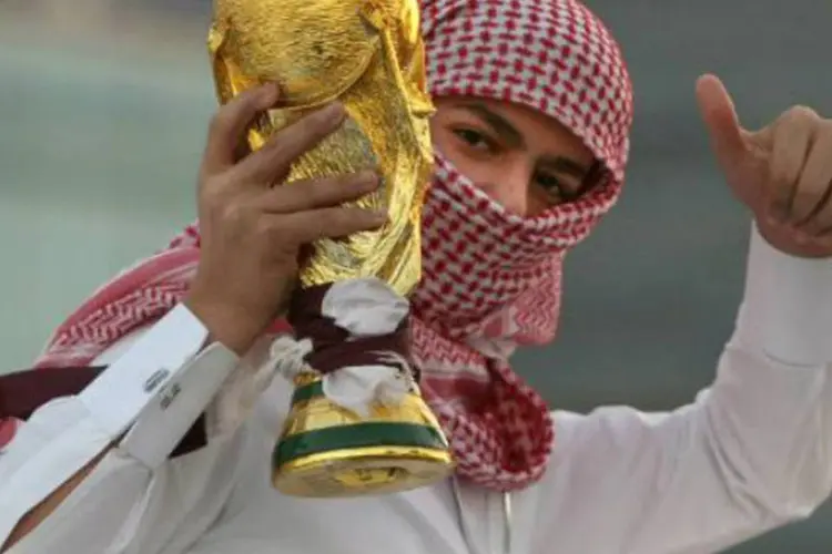 
	Jovem segura uma r&eacute;plica da ta&ccedil;a da Copa do Mundo em Doha, no Catar
 (Marwan Naamani/AFP)