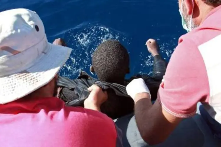 Membros da Guarda Costeira líbia resgatam um imigrante após o naufrágio (Mahmud Turkia/AFP)