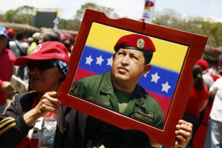 Mulher carrega retrato de Hugo Chávez: nas proximidades do local do desfile, camelôs venderam diversos produtos referentes ao líder falecido no ano passado (Jorge Silva/Reuters)