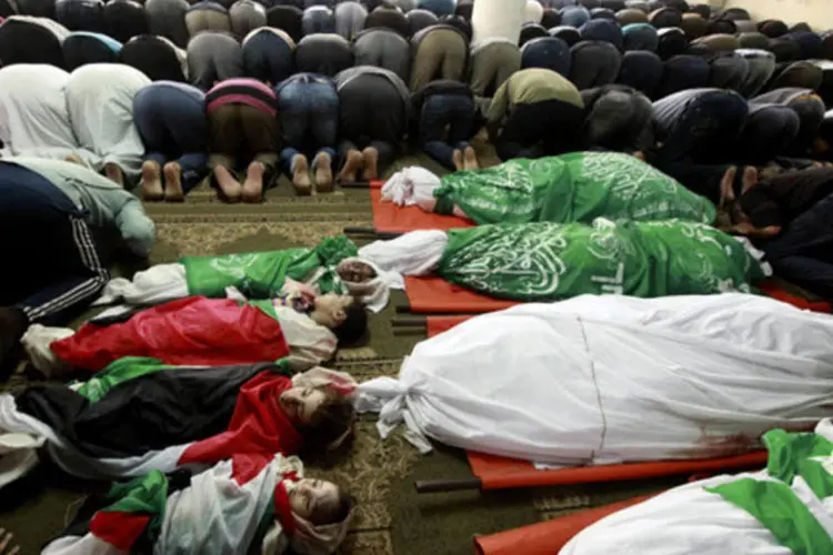 
	Palestinos rezam pelos parentes mortos durante um funeral em Gaza, na Palestina
 (Mohammed Salem/Reuters)