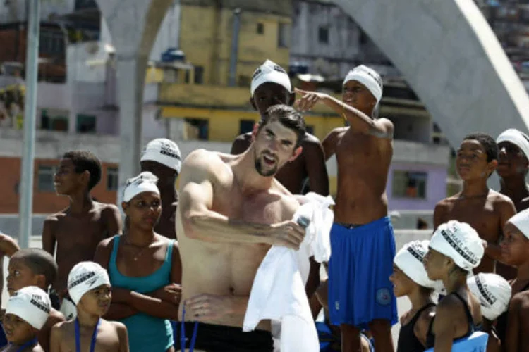 O nadador olímpico dos Estados Unidos Michael Phelps posa com crianças durante uma visita ao complexo da Rocinha   (REUTERS / Pilar Olivares)