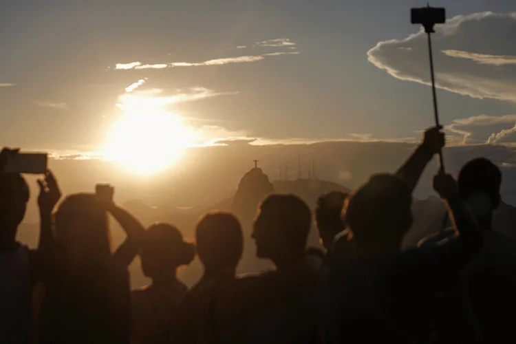 Turistas veem o Cristo Redentor ao fundo em pôr do sol no Rio (Mario Tama/Getty Images)