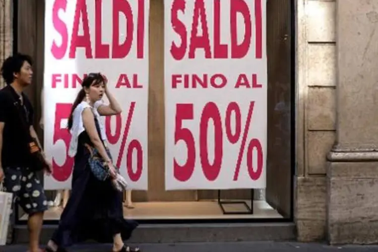 Casal caminha ao lado de vitrine de loja anunciando promoção em Roma (Filippo Monteforte/AFP)