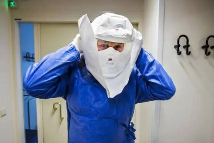 Médico coloca roupa de proteção contra ebola: OMS renovou a direção para África na tentativa de ampliar ofensiva de combate ao ebola (Remko de Waal/AFP)