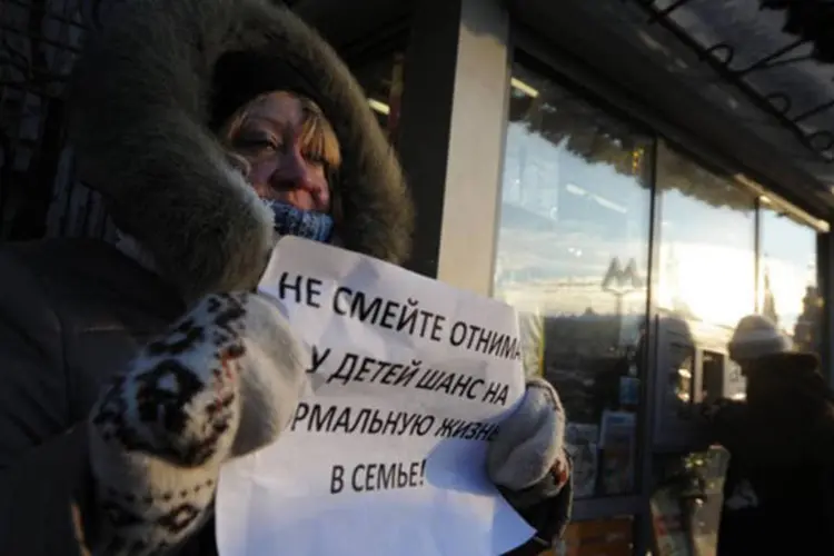 
	Mulher segura cartaz de protesto em frente ao parlamento russo, que aprovou a lei proibindo que norte-americanos adotem crian&ccedil;as do pa&iacute;s
 (©afp.com / Andrey Smirnov)