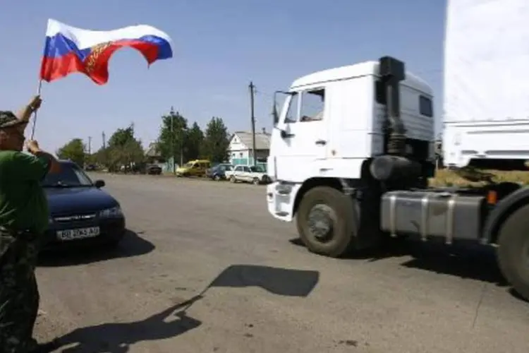 
	Homem exibe bandeira russa durante passagem de comboio na Ucr&acirc;nia
 (Sergey Venyavsky/AFP)