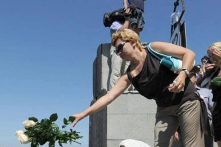 Mulheres jogam flores nas águas do Rio Volga, numa homenagem às vítimas do naufrágio (Natalia Kolesnikova/AFP)