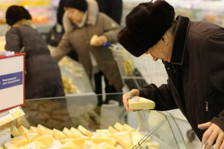 
	Russo escolhe uma pe&ccedil;a de queijo em um supermercado de Prokopyevsk, na R&uacute;ssia
 (Andrey Rudakov/Bloomberg)