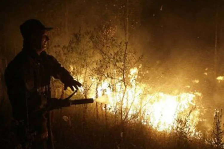 Russo tenta apagar incêndio na cidade de Murmino no forte verão russo, em agosto de 2010: a década também foi marcada por fenômenos extremos
 (Artyom Korotayev/AFP)