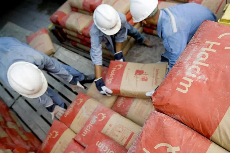 
	Trabalhadores empilhando sacos de cimento em uma distribuidora da Holcim: empresa teve queda no lucro operacional subjacente no segundo trimestre
 (Kemal Jufri/Bloomberg News)