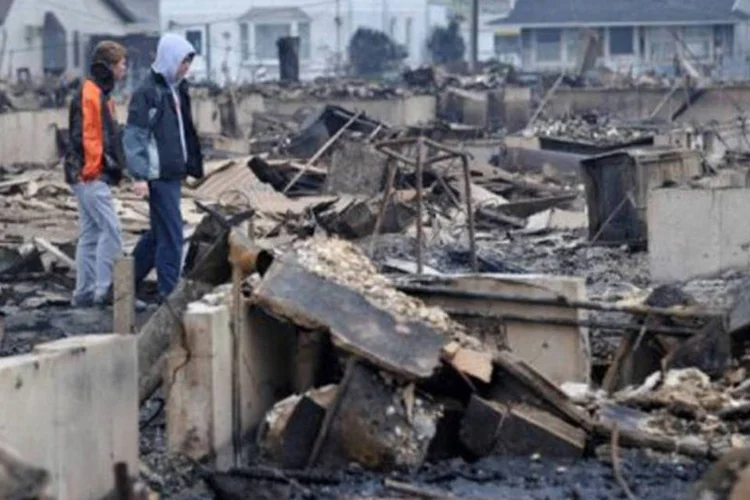 
	Meninos observam &aacute;rea destru&iacute;da no Queens pela passagem da supertempestade por Nova York: preju&iacute;zos foram estimados em 19 bilh&otilde;es de d&oacute;lares na cidade
 (Stan Honda/AFP)