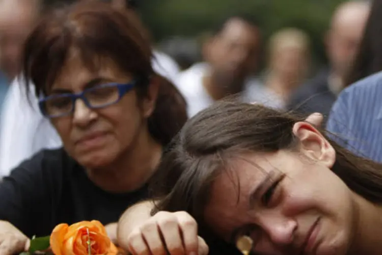 Anna Carolina (D), filha de Daniele Dias de Mattos, vítima do incêndio na boate Kiss em Santa Maria, chora sobre o caixão da mãe em cemitério do Rio de Janeiro (REUTERS / Pilar Olivares)
